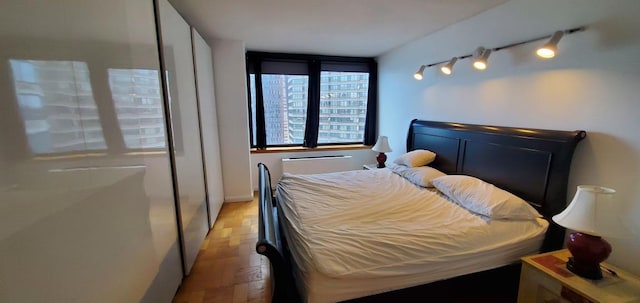 bedroom with light wood-style floors and track lighting