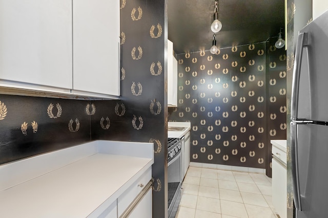 kitchen with white cabinets, light tile patterned floors, stainless steel appliances, and light countertops