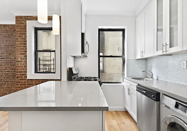 kitchen featuring appliances with stainless steel finishes, white cabinetry, hanging light fixtures, and washer / dryer