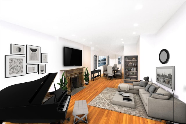 living area with recessed lighting, a fireplace with flush hearth, and wood finished floors