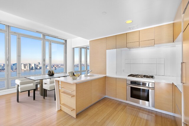 kitchen featuring sink, stainless steel oven, kitchen peninsula, gas stovetop, and a water view