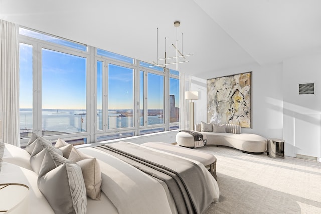 bedroom featuring multiple windows, a water view, and a chandelier