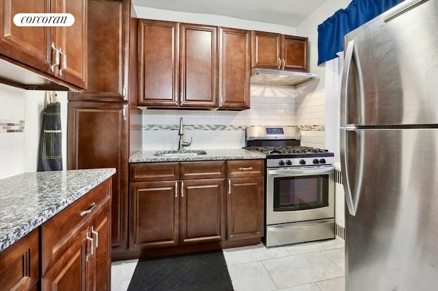 kitchen with light tile patterned floors, appliances with stainless steel finishes, backsplash, light stone counters, and sink