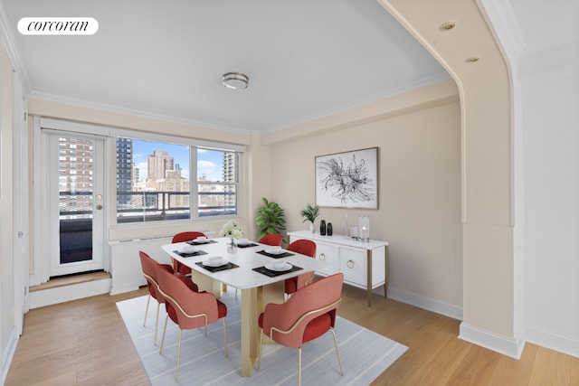 dining space with light hardwood / wood-style flooring and ornamental molding