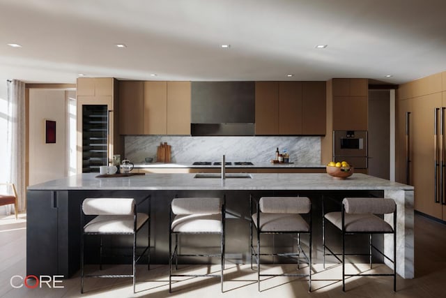 kitchen featuring a spacious island, a kitchen breakfast bar, tasteful backsplash, and wall chimney range hood