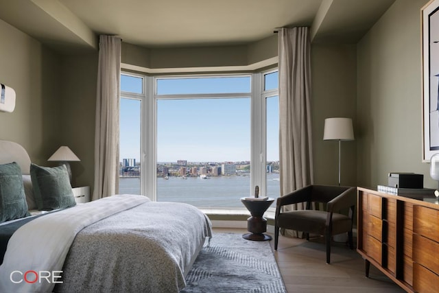 bedroom with wood-type flooring and a water view