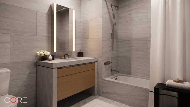 full bathroom featuring tiled shower / bath, tile walls, vanity, and toilet