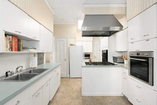 kitchen with wall chimney range hood, sink, white cabinets, and white fridge