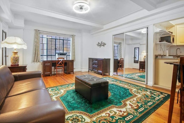 living room with beamed ceiling and light wood-type flooring