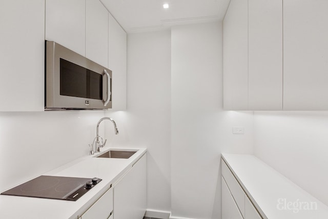 kitchen with white cabinetry, black electric stovetop, and sink