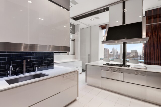 kitchen featuring sink, light tile patterned floors, white cabinets, and backsplash