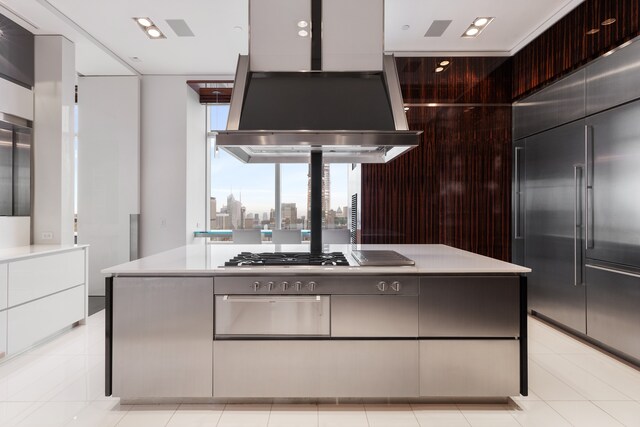 kitchen with built in refrigerator, island exhaust hood, a center island, stainless steel gas cooktop, and light tile patterned flooring