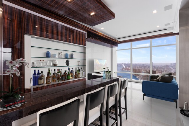 bar with floor to ceiling windows, a water view, and dark brown cabinetry