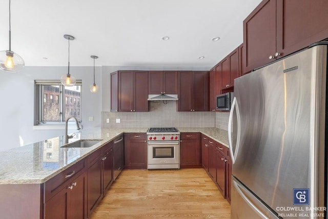 kitchen featuring pendant lighting, sink, appliances with stainless steel finishes, light stone counters, and kitchen peninsula