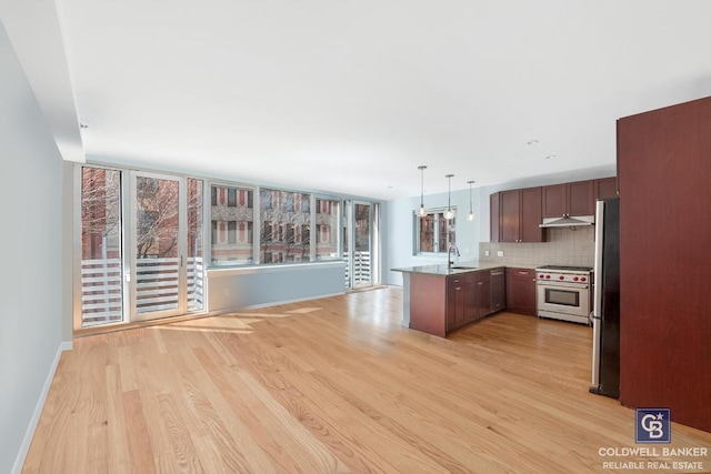 kitchen with sink, appliances with stainless steel finishes, kitchen peninsula, pendant lighting, and backsplash