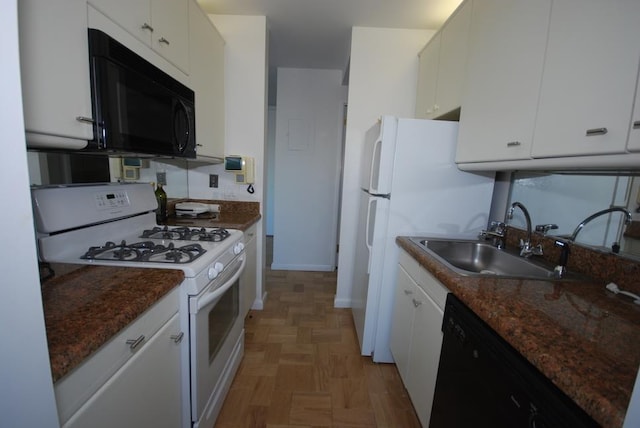 kitchen featuring dark stone counters, white cabinetry, a sink, and black appliances