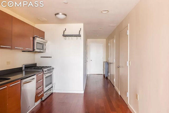 kitchen with appliances with stainless steel finishes and dark hardwood / wood-style flooring