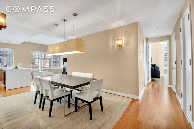 dining space with light wood-type flooring and baseboards