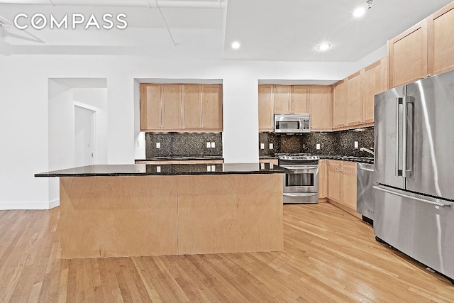 kitchen featuring light hardwood / wood-style flooring, light brown cabinets, dark stone counters, a kitchen island, and stainless steel appliances