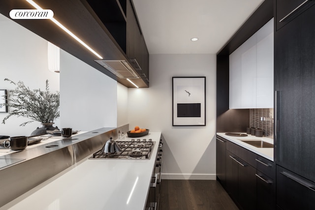 kitchen featuring dark hardwood / wood-style floors, stainless steel gas stovetop, tasteful backsplash, white cabinetry, and sink