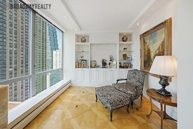 sitting room with light parquet flooring, plenty of natural light, built in features, and baseboard heating