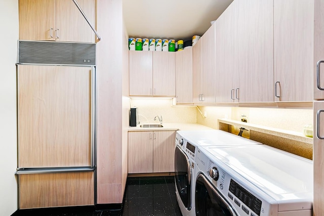 laundry area featuring a sink, cabinet space, dark tile patterned flooring, and washing machine and dryer