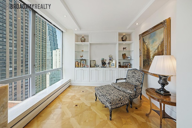 sitting room featuring recessed lighting, built in shelves, and a baseboard heating unit