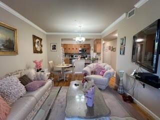 living room featuring a notable chandelier, ornamental molding, and light wood-type flooring