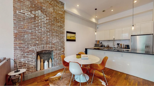 kitchen with white cabinetry, hanging light fixtures, dark wood-type flooring, and stainless steel fridge