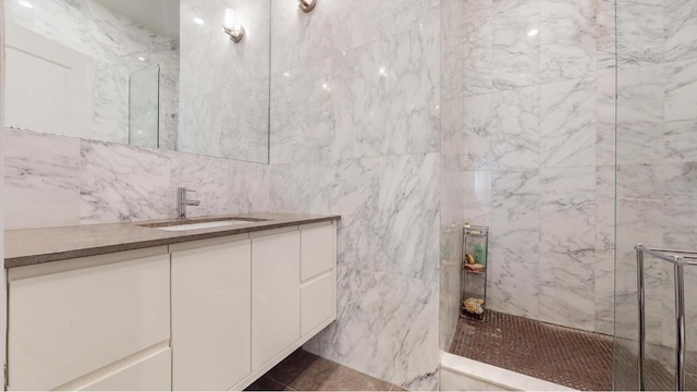 bathroom with vanity, tiled shower, and tile walls