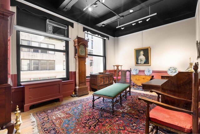 living area featuring wood-type flooring, rail lighting, and decorative columns