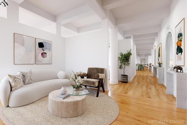 living area with baseboards, wood finished floors, and beamed ceiling