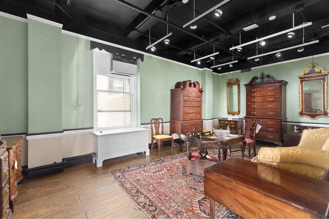 living area featuring crown molding, track lighting, a wall mounted AC, and hardwood / wood-style floors