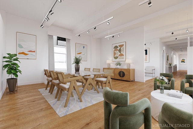 dining room featuring light wood finished floors, rail lighting, and baseboards