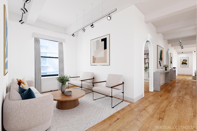 living area with beamed ceiling, track lighting, and light hardwood / wood-style flooring