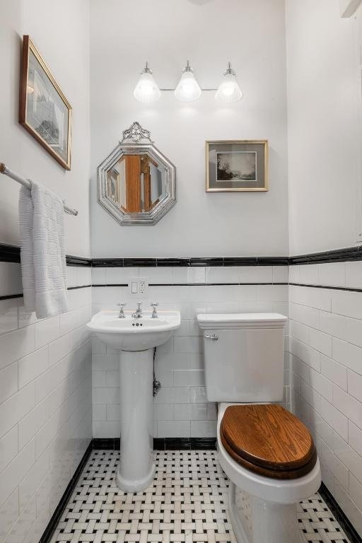 bathroom with toilet, tile patterned flooring, and tile walls