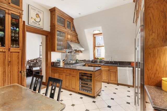 kitchen with appliances with stainless steel finishes, sink, beverage cooler, dark stone counters, and kitchen peninsula