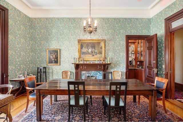 dining area with hardwood / wood-style flooring, ornamental molding, and a notable chandelier