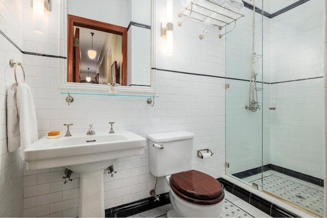 bathroom featuring tile walls, a shower with door, and toilet