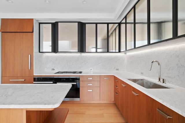 kitchen featuring decorative backsplash, oven, sink, and light stone countertops