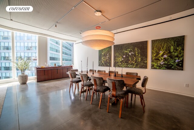 dining area featuring track lighting, floor to ceiling windows, and concrete flooring