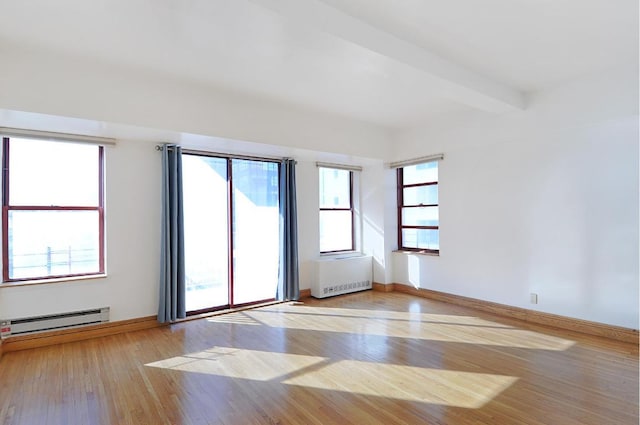 empty room with beam ceiling, baseboard heating, and light hardwood / wood-style floors