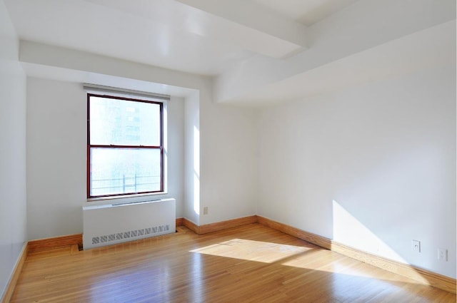 spare room featuring radiator heating unit and light wood-type flooring