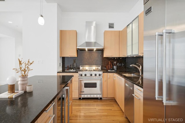 kitchen with wall chimney range hood, sink, hanging light fixtures, wine cooler, and premium appliances