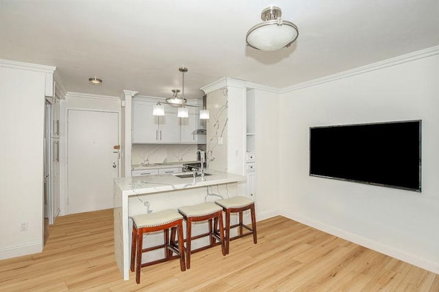 kitchen with ornamental molding, a peninsula, a kitchen breakfast bar, and a sink