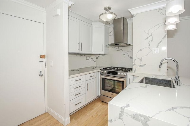 kitchen with gas range, wall chimney exhaust hood, decorative backsplash, and white cabinets