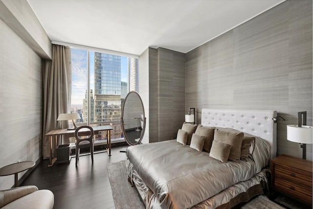 bedroom with floor to ceiling windows, dark hardwood / wood-style flooring, and multiple windows