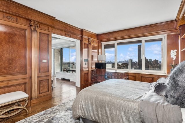 bedroom with a city view, a decorative wall, and wood finished floors