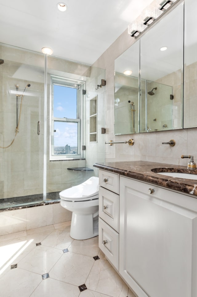 303 E 57th St Unit 45G, New York City, NY 10022 - bathroom with tile walls, vanity, a shower stall, toilet, and tile patterned flooring