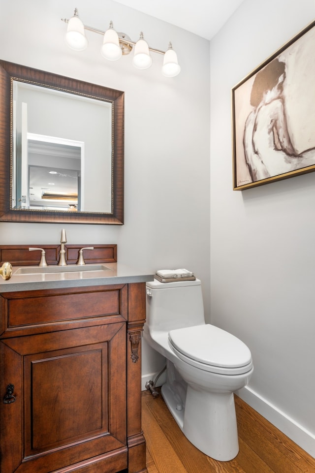 bathroom with vanity, toilet, wood finished floors, and baseboards